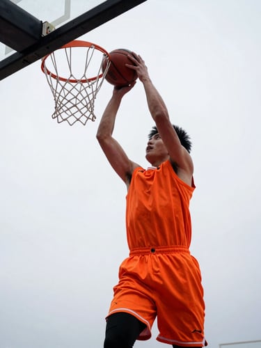 Low-angle dynamic shot of a young basketball player driving to the hoop, high contrast natural light, safety orange jersey, determination, 35mm