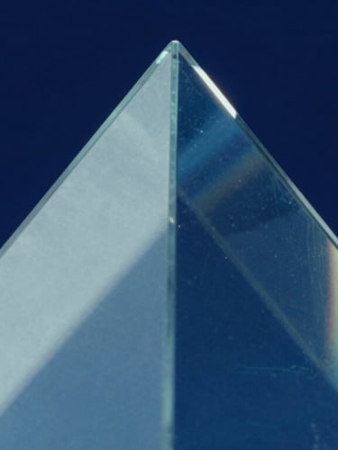 Extreme macro detail of light refracting through a triangular glass prism, cool blue and deep navy shadows, sharp focus, 35mm.