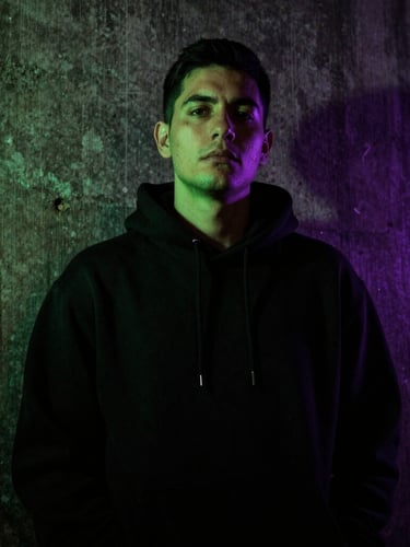 Low-angle gritty portrait of SergioMdrz in a dark concrete alley, wearing a black hoodie, neon green gel light casting sharp shadows, high contrast, 35mm photography