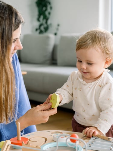 Una niñera profesional de la agencia Nanny Heart, y una niña pequeña, juegan en casa con una mesa de