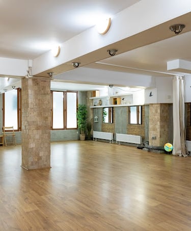 Sala de practică a centrului de yoga Alchimia Vieții din București, spațiu luminos cu oglinzi și plante