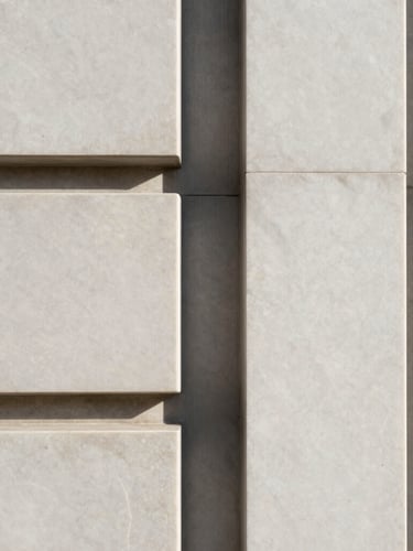 Portrait-oriented close-up of honed marble and brushed steel architectural detail, crisp high-contrast daylight, sharp focus, minimalist neutral tones, sleek architectural photography.