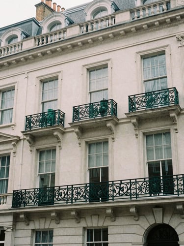 Architectural detail of a classic London office building facade in Fitzrovia, overcast daylight, soft shadows, deep green ironwork, muted desaturated tones, 35mm film photography