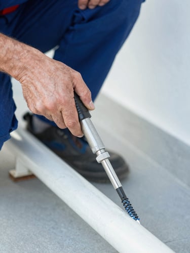 Close-up of a professional plumber's hands using a mechanical drain snake to clear a pipe, clean work clothes, sharp focus, natural daylight.