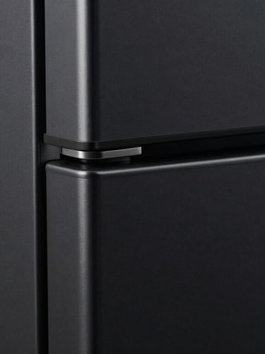 Extreme close-up of a flawless matte black refrigerator corner wrapped in premium automotive vinyl, sharp clean edges, dramatic side lighting highlighting the metallic texture, absolute precision, no bubbles.