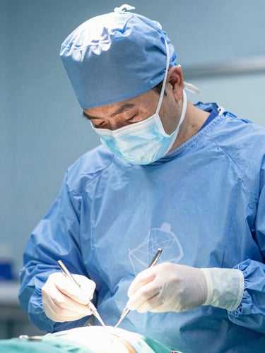 Close-up of a professional clinical instructor in sterile blue scrubs demonstrating surgical instrumentation under cool bright studio lighting, sharp focus, 50mm lens.