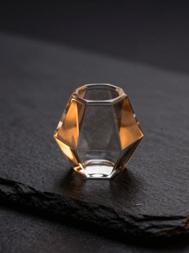 Macro shot of a clean, geometric glass pipe on a dark slate surface, warm amber lighting from the side, sharp focus, 50mm lens