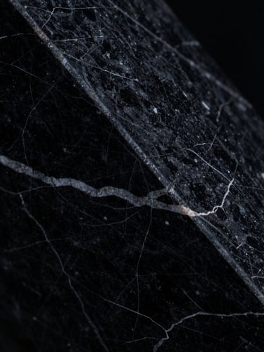 Macro close-up of dark marble textures with high-contrast directional light and deep shadows, 35mm