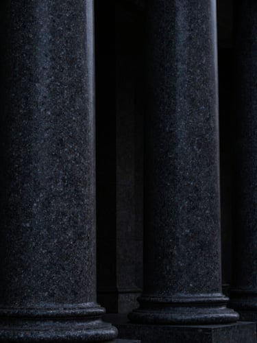 Low-key high-contrast macro photography of dark granite columns, deep shadows, structural finance architecture, 35mm