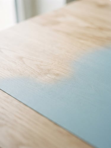 Close-up of a matte pastel laminate surface of a gaming desk, with light birch wood grain visible, natural daylight, soft shadows, 35mm lens.