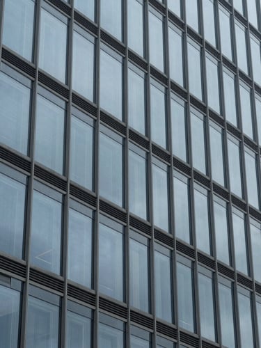 Macro detail of a modern steel and glass skyscraper facade, clean geometric patterns, cool overcast light, architectural stability, 35mm