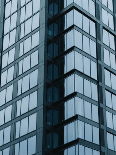 Minimalist architectural photography of a modern financial district building, cool overcast daylight, sharp geometric lines, desaturated blue and slate tones, 35mm