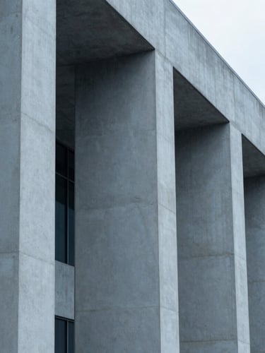 Abstract architectural detail of concrete and steel pillars, clean geometric lines, cool overcast daylight, minimalist corporate aesthetic, desaturated blue and slate tones
