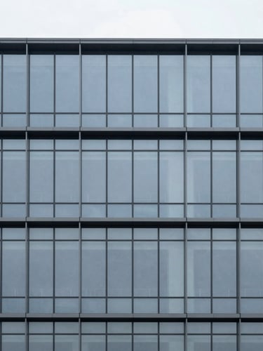 Minimalist architectural photography of a modern corporate building facade, clean geometric glass and steel lines, cool overcast daylight, desaturated slate tones, sharp focus, 35mm