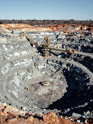 Aerial wide environmental shot of an active open-cut gold mine in Western Australia, harsh natural daylight, deep shadows, desaturated metallic tones, 35mm.
