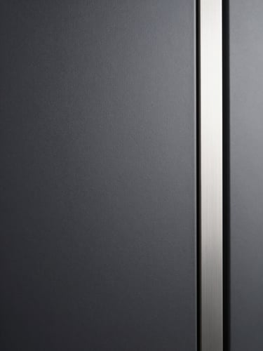 Close-up of the machine's matte charcoal panel surface under even soft studio light, brushed metal interaction strip visible at the right edge, no reflections, architectural minimalism, tight framing