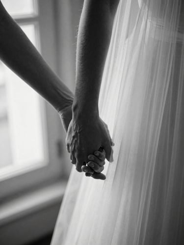 Primer plano artístico en blanco y negro de manos entrelazadas con un velo de novia sutilmente iluminado por luz de ventana lateral, grano fino cinematográfico, alto contraste.