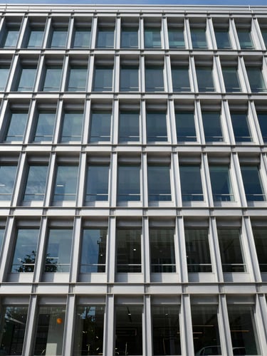 Straight-on architectural elevation of a modern commercial building under crisp daylight, steel framing visible, high contrast geometric shadows