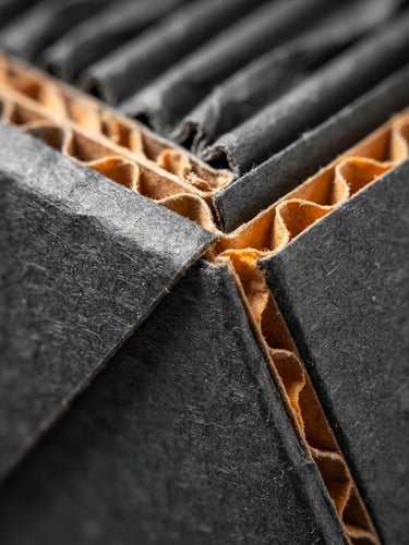 Extreme macro close-up of sharp structural folds on a pristine dark gray corrugated carton, bright clean-room industrial lighting, technical depth of field