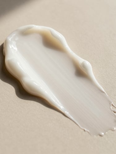 Extreme close-up of a luxurious, silky cream texture being swiped on a warm, minimalist surface. Soft, diffused natural daylight with delicate shadows, highlighting clean formulation.