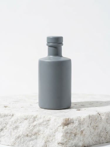 A minimalist slate gray bottle on a raw, textured white stone slab, bright high-key clinical lighting, soft clean shadows, 50mm lens