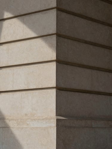 Abstract architectural detail of a classic stone facade with deep geometric shadows, soft indirect natural light, elegant and sober, 35mm photography.