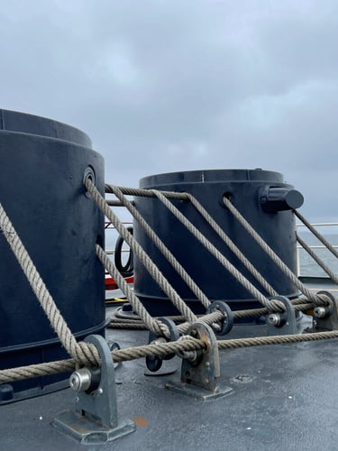 A close-up of heavy-duty steel mooring ropes and marine deck equipment on a ship, industrial texture, overcast daylight