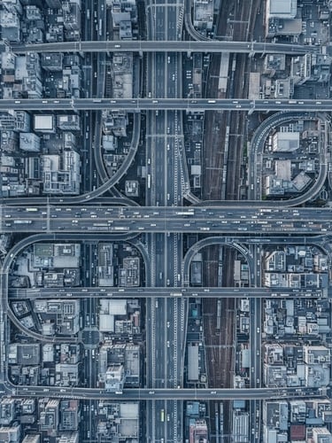 Wide-angle orthographic view of a complex, high-density urban infrastructure grid, cool diffused daylight, desaturated blue and slate tones, sharp focus, no text.