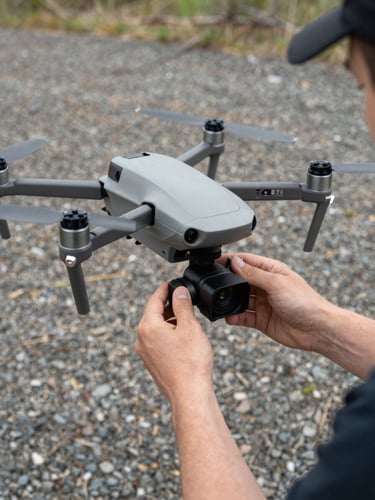 Close overhead shot of a drone mounted with a mapping camera on a gravel survey pad, operator hands adjusting the gimbal, natural daylight, equipment detail sharp against a muted earth background