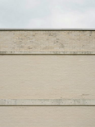 Straight-on architectural crop of a brick and concrete building facade, clean lines, soft natural overcast daylight, minimal composition, 35mm lens