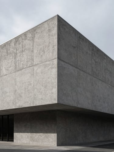 Wide architectural angle of a modern concrete building facade with clean geometric lines, dramatic overcast side lighting and deep shadows, sober editorial style, 35mm lens