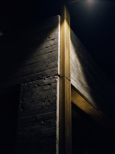 Dramatic low-key architectural detail of a modern concrete facade, sharp directional light, deep obsidian and gold tones, 35mm film