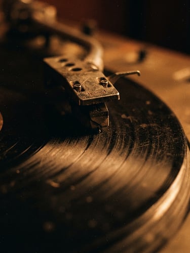 Macro close-up of a dusty turntable needle resting on worn vinyl grooves under warm ember lighting, gritty 35mm film grain.