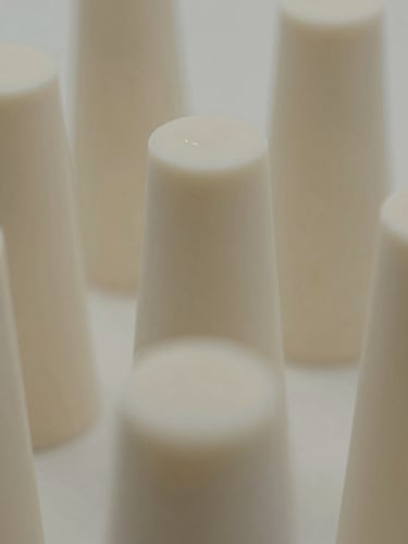 Close-up of raw liquid silicone curing in a cleanroom, soft architectural shadows, warm neutral tones, minimalist product photography.