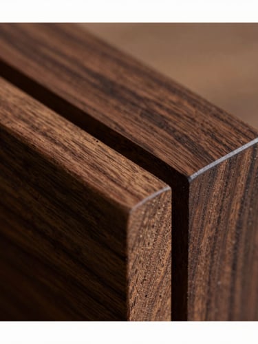 Macro close-up of a mortise-and-tenon joint in deep walnut wood, highlighting the rich natural grain and precise craftsmanship under soft directional light.
