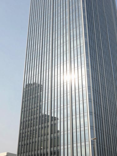 Wide architectural crop of a modern Dubai business tower glass facade reflecting the bright morning sun, clean corporate lines, negative space on the left, 35mm professional photography