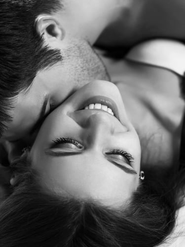 Man kissing a woman's neck. She's smiling
