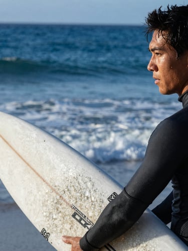 Close-up of a focused athlete preparing on the beach, holding a surfboard under cold morning light, sharp focus, 35mm sports photography.