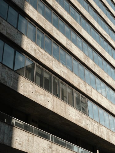 Wide architectural crop of modern concrete and glass building facade in São Paulo, sharp geometric shadows, bright natural daylight.