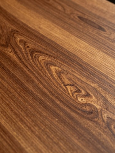 Close-up of polished premium teak wood grain, catching sharp golden-hour highlights, showing rich texture and craftsmanship.