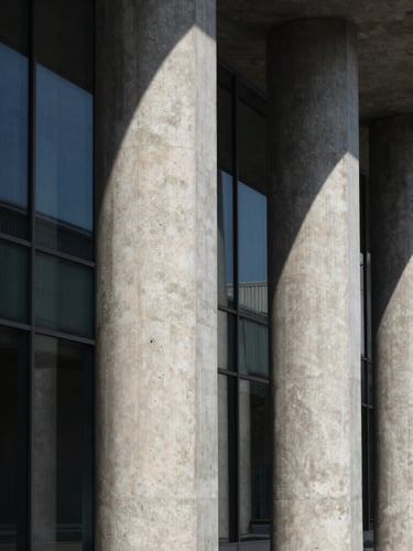 Dramatic architectural geometry of concrete columns and glass panels, sharp shadows, high contrast