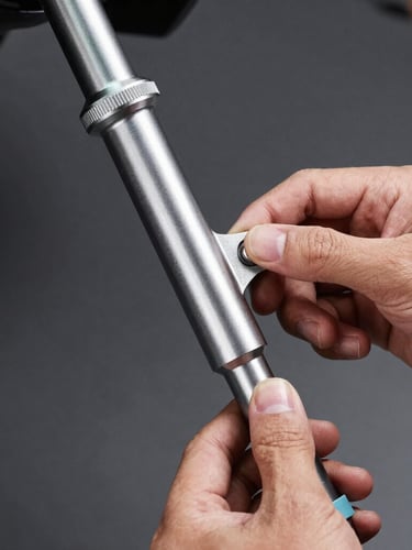 Eye-level shot of a mechanic's hands inspecting a newly installed steel steering link stabilizer on a car chassis, bright industrial lighting, focus on metallic textures