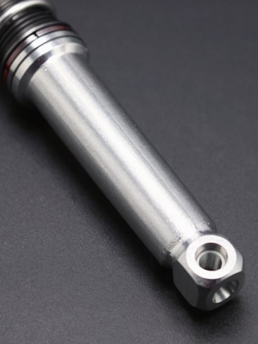 Close-up of a high-performance metallic silver shock breaker, sharp industrial studio lighting, high contrast, dark gray background