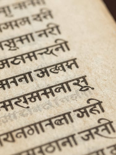 Close-up of ancient Sanskrit manuscript on textured aged parchment, soft library light, macro details, archival editorial photography