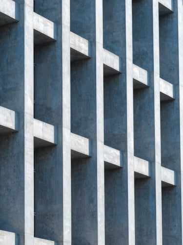 Sharp architectural photography of a modern building facade in Rio de Janeiro, highlighting structural columns, clean daylight, cool blue tones