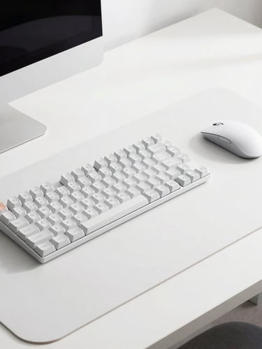 A sleek modern desk setup with a mechanical keyboard, wireless mouse, and minimal desk mat, bright natural light, crisp studio focus, high-key product photography