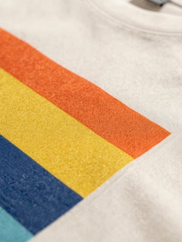 Close-up macro shot of premium t-shirt fabric texture and crisp, vibrant graphic print stitching, warm natural daylight, shallow depth of field.