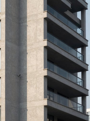 Architectural detail of a modern high-rise development facade, sharp morning shadows, clean geometric concrete lines, 35mm architectural lens, muted corporate tones