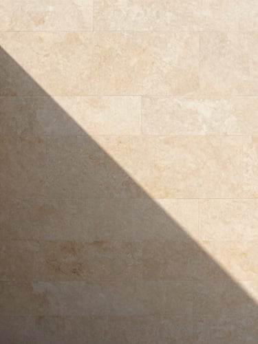 Minimalist architectural detail of a warm stone wall, sharp geometric shadow cast by soft daylight, clean lines, elegant and serene, 35mm photography