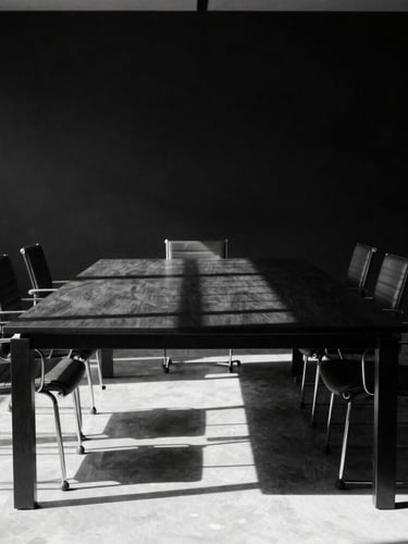 An empty executive boardroom in Milan, hard directional light casting dramatic linear shadows across a minimalist black table, high-contrast black and white photography.